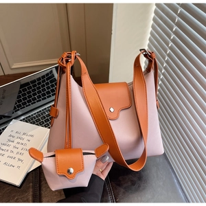 Pink shoulder bag and mini pouch set with orange leather straps on an office desk