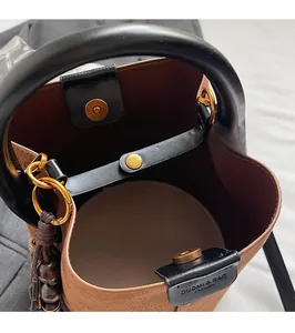 Détail du sac seau en daim marron avec fermeture magnétique et boucles dorées