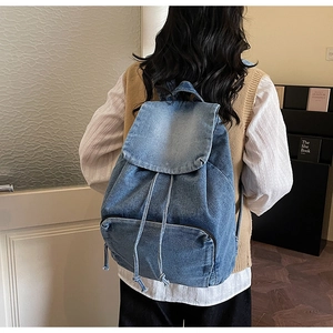 Macro view of blue denim backpack showing drawstring closure and vintage washed texture