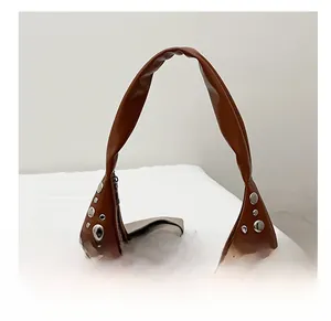 Détail de la bandoulière en cuir marron avec rivets argentés sur ce sac seau élégant
