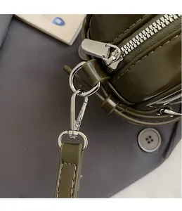 Détails des crochets métalliques argentés et du cuir vert olive sur le sac à main