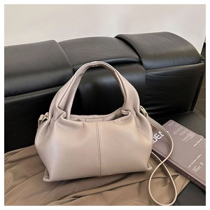 Detail of a beige pleated cloud bag in textured leather with a slim shoulder strap