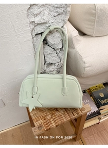 Detail of light green baguette bag with star charm on a wooden stool in a home setting