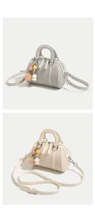 Détail de sacs Boston en gris clair et blanc crème avec des breloques en étoile