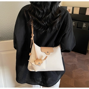 Detail of a beige canvas crossbody bag set with brown PU leather trim on a model