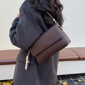 Détail d'un sac à bandoulière en cuir marron foncé avec perles et décor de feuilles d'automne