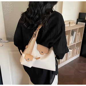 Detail of beige canvas and brown leather underarm bag with a detachable mini pouch