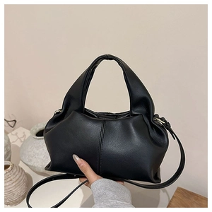 Detailed view of black minimalist dumpling bag with pleated sides and gold hardware