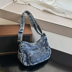 Detail of floral denim shoulder bag featuring dual zippers and adjustable strap