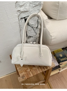 Detail of white minimalist leather shoulder bag with a stylish star-shaped charm