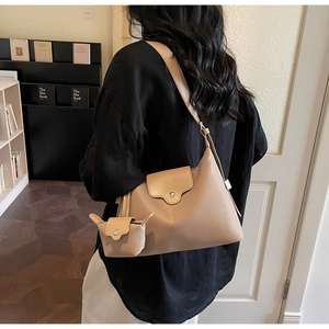 Detail view of beige crossbody bag set with matching mini pouch in cozy bookstore setting