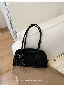 Detail of black suede shoulder bag featuring white contrast stitching and star charms