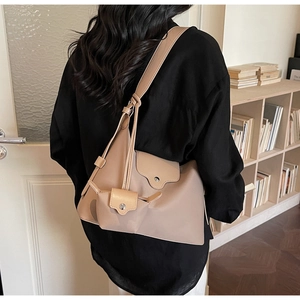 Khaki nylon tote bag with small pouch shown on model in a cozy indoor setting