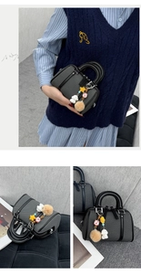Détail du sac Boston gris avec poignées en cuir noir et breloques en peluche mignonnes