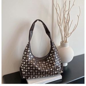 Nahaufnahme braune Hobo-Tasche aus Leder mit silbernen Nieten auf Buch-Hintergrund
