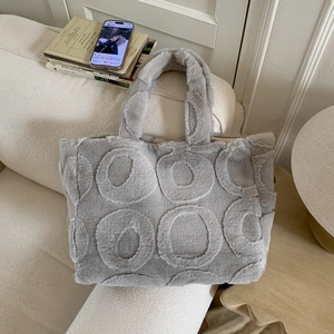 Detail of light grey plush tote bag with circular embossed patterns on a soft sofa