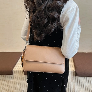Vue latérale du sac à bandoulière beige avec détail de breloque en perles de bois