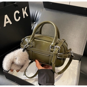 Detail of dark olive green patent leather bag with plush rabbit charm in gift box