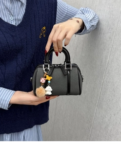 Gros plan détaillé du sac Boston gris foncé avec breloques mignonnes et poignées en cuir