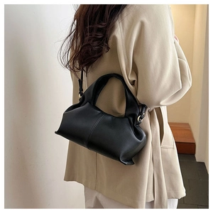 Detail of a black leather cloud crossbody bag shown from behind on a trench coat