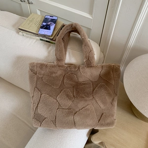 Detailed view of brown plush tote bag with geometric embossed pattern on a sofa