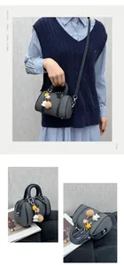 Détail du sac Boston avec texture tissée, breloque en peluche et bandoulière ajustable