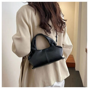 Detailed back view of a chic black pleated cloud bag on a beige blazer model outfit