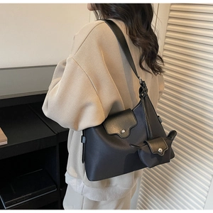 Close-up of black leather shoulder bag with matching mini pouch and silver metal buckles