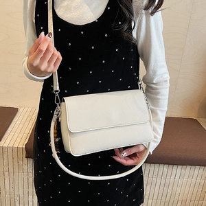 Détail d'un sac à bandoulière rectangulaire blanc crème avec cuir à motif litchi