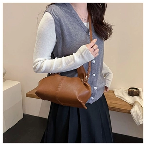 Detail of a brown pleated leather crossbody cloud bag styled on a female model