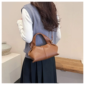 Brown leather cloud bag with soft pleats shown on model in a minimalist setting