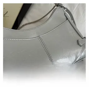 Detalle del bolso hobo plateado con cuero metálico plisado y correa de cadena fina