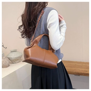 Brown pleated dumpling bag shown on a model in a minimalist lifestyle setting