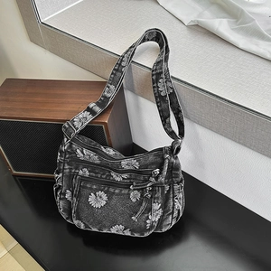 Close-up of vintage denim crossbody bag featuring white daisy print and functional zippers