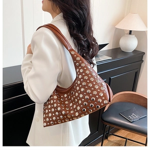 Détail d'un sac d'épaule en cuir marron avec rivets argentés sur fond intérieur moderne