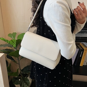 Détail du sac blanc texture litchi avec fermoirs argentés et rabat élégant pour femme