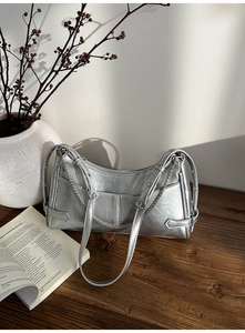 Detalle del bolso de hombro plateado metalizado con textura agrietada y cadena