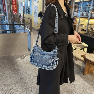 Macro view of distressed blue denim fabric with white floral cutout details on a crossbody bag