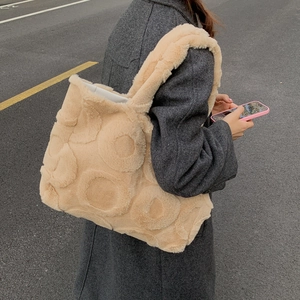 Beige faux fur tote bag with textured polka dots carried by a model in a gray coat