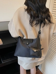 Black nylon crossbody bag with adjustable strap and coin purse in casual studio setting
