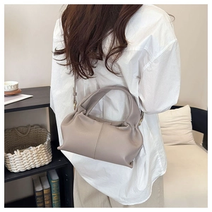 Detail of soft beige cloud bag featuring pleated faux leather and adjustable slim strap