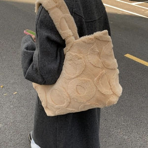 Detail of plush tote bag featuring beige faux fur and large embossed circle patterns