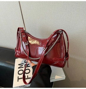 Detalle del bolso de cuero vintage rojo oscuro con cadena de plata y hebillas de metal