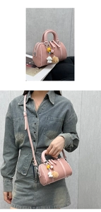 Détail du sac Boston rose montrant la texture tissée, les charms et le porté en bandoulière