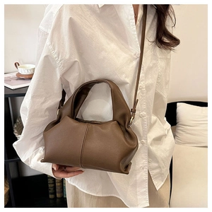 Brown cloud-style pleated crossbody bag shown on model with neutral fashion attire