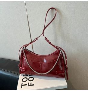 Detalle de bolso medialuna en charol rojo con cadena plateada y correa ajustable