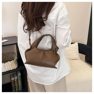 Brown leather crossbody cloud bag with pleated details shown on model in home setting