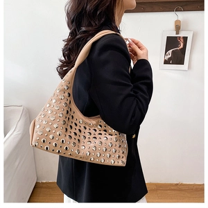 Detail der beige Schultertasche mit silbernen Nieten an einem Model im schwarzen Blazer