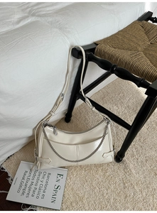 Detalle de bolso de hombro en ecopiel blanco crema con cadena plateada sobre silla