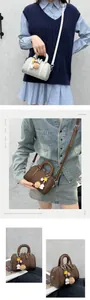 Détail du sac Boston avec breloques en peluche et bandoulière réglable en cuir souple